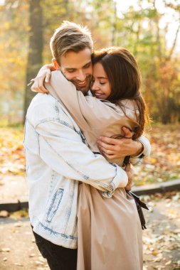 Çekici beyaz bir çiftin gülen ve sonbahar parkında birlikte yürüdüğü görüntüsü.