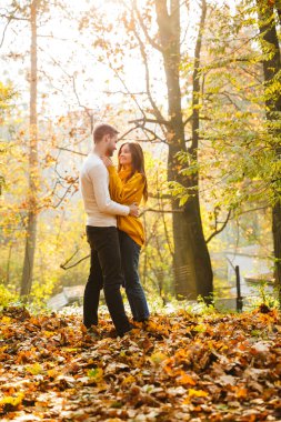 Çekici beyaz bir çiftin gülen ve sonbahar parkında birlikte yürüdüğü görüntüsü.