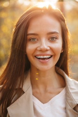 Güz parkında yürüyen güzel, gülümseyen bir genç kadına yaklaş.