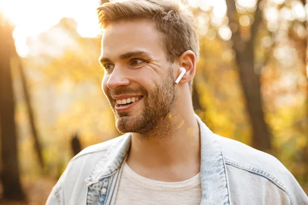 Imagem Belo Jovem Caucasiano Casaco Ganga Sorrindo Usando Fones Ouvido — Fotografia de Stock