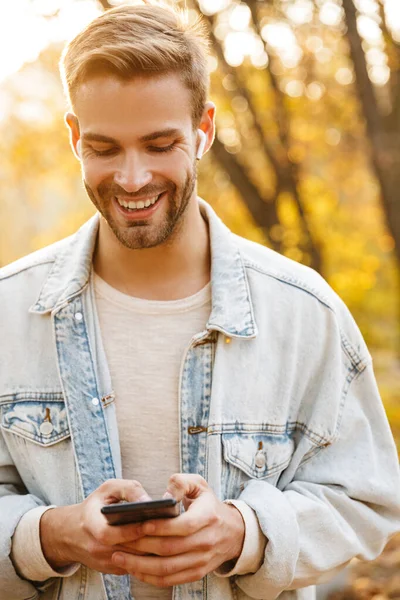 Immagine Bel Giovane Caucasico Auricolare Che Sorride Usa Smartphone Mentre — Foto Stock