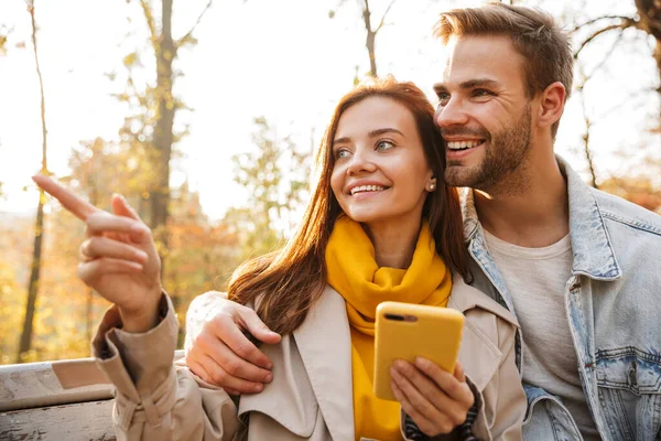 Весела Молода Пара Сидить Лавці Осінньому Парку Використовуючи Мобільний Телефон — стокове фото