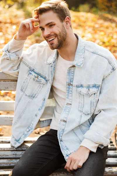 Schöner Lächelnder Junger Mann Sitzt Auf Einer Bank Herbstlichen Park — Stockfoto