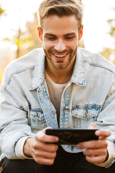 Handsome Smiling Young Man Sitting Bench Autumn Park Using Mobile — Stock Photo, Image