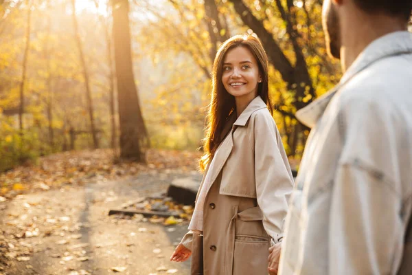 美丽的年轻夫妇手牵手在秋天的公园里散步 — 图库照片