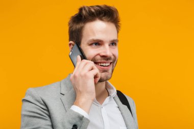 Sarı arka planda tek başına duran yakışıklı, gülümseyen genç iş adamı ceketi.