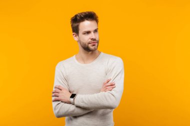 Çekici genç adam sarı arka planda tek başına duruyor, başka tarafa bakıyor.