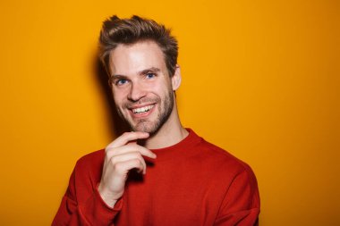 Çekici mutlu genç adam sarı arka planda tek başına duruyor.