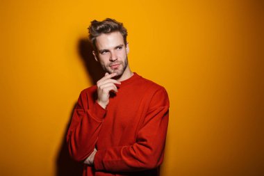 Çekici düşünceli genç adam sarı arka planda tek başına duruyor.