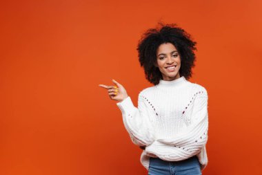 Heyecanlı, genç, Afrikalı bir kadın kırmızı arka planda tek başına duruyor.