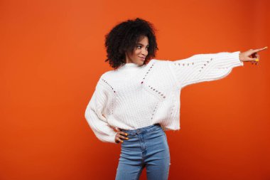 Heyecanlı, genç, Afrikalı bir kadın kırmızı arka planda tek başına duruyor.