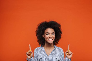 Heyecanlı, genç, Afrikalı bir kadın kırmızı arka planda tek başına duruyor.