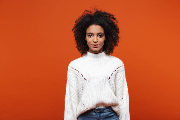 Beautiful smiling young african woman wearing sweater standing islolated over red background