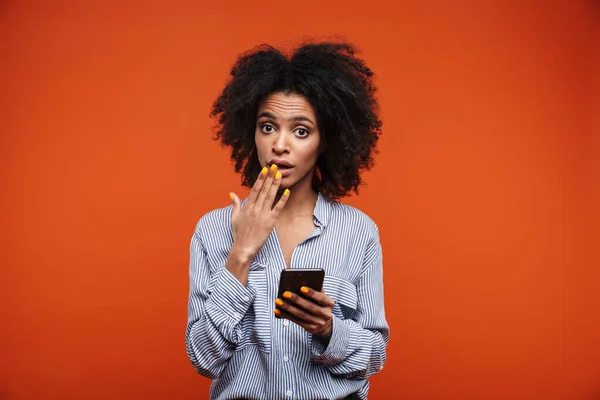 Verwirrte Junge Afrikanerin Benutzt Handy Isoliert Über Rotem Hintergrund — Stockfoto