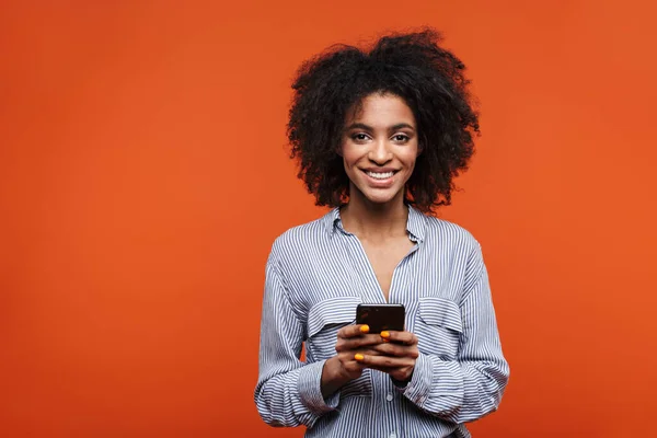 Kırmızı Arka Planda Izole Edilmiş Cep Telefonu Kullanan Gülümseyen Afrikalı — Stok fotoğraf