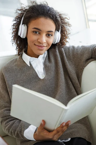 Kafedeki Kanepede Otururken Kulaklık Takan Kitap Okuyan Güzel Afro Amerikan — Stok fotoğraf