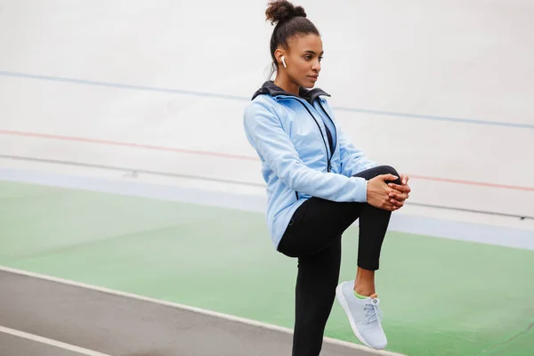 Beautiful Young Fit African Sportswoman Wearing Wireless Earphones Doing Stretching — Stock Photo, Image