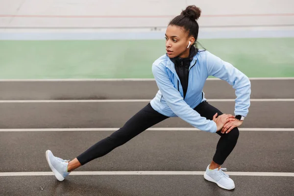 Beautiful Young Fit African Sportswoman Wearing Wireless Earphones Doing Stretching — Stock Photo, Image