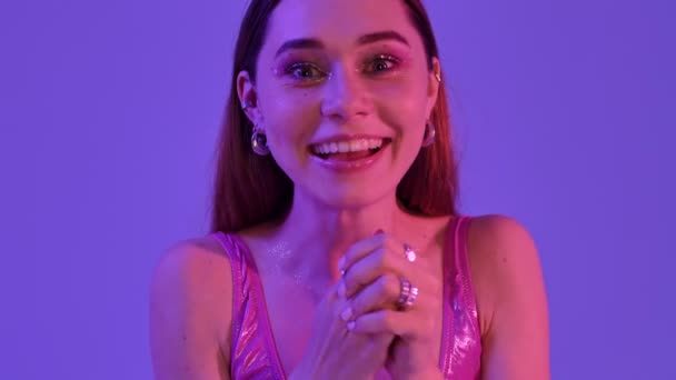 一个快乐的女人 有着时尚艳丽的妆容 在紫色的霓虹灯的衬托下 做出了一个成功的姿态 — 图库视频影像
