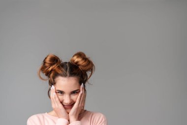 Gri arka planda izole edilmiş sevimli, neşeli, genç bir kızın portresi.