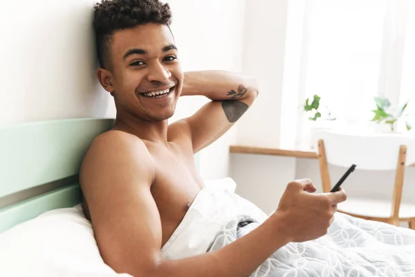 Εικόνα Του Αισιόδοξου Χαρούμενος Νεαρός Αφρικανός Πρωί Στο Υπνοδωμάτιο Χρησιμοποιώντας — Φωτογραφία Αρχείου