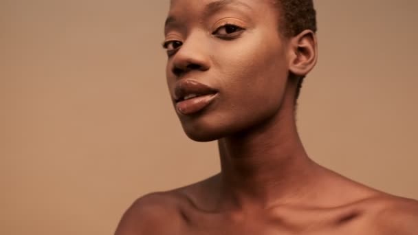 性感漂亮的半裸非洲女人 黑色短发 摆姿势 环视米色背景 — 图库视频影像
