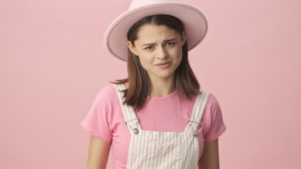 動揺かわいいですブルネット女性で全体と帽子ジェスチャーと周りを見ますピンクの背景 — ストック動画