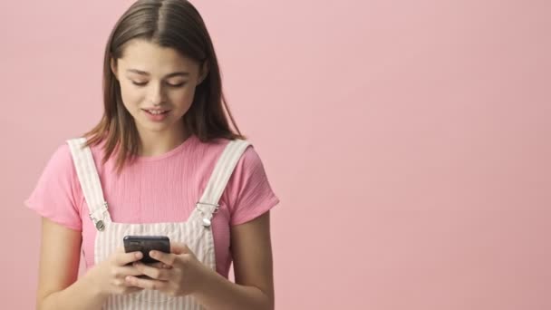 Wesoły Ładna Brunetka Kobieta Kombinezonie Pomocą Smartfona Patrząc Różowe Tło — Wideo stockowe