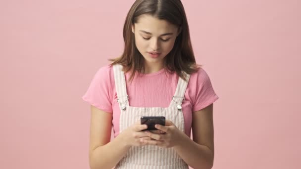 Ηρεμία Όμορφη Μελαχρινή Γυναίκα Φόρμες Χρησιμοποιώντας Smartphone Πάνω Από Ροζ — Αρχείο Βίντεο
