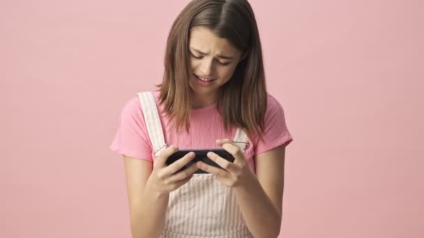 Concentrated Pretty Brunette Woman Overalls Playing Smartphone Becoming Happy Pink — Stock Video