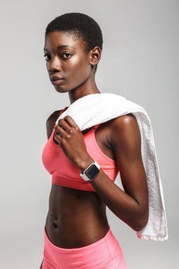 Beyaz arka planda izole bir şekilde çalışırken havluyla su içen Afrikalı Amerikalı sporcu.