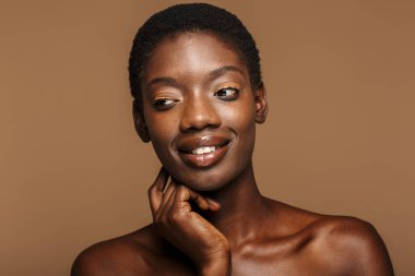 Çekici, yarı çıplak, kısa siyah saçlı, bej arka planda yaşayan Afrikalı bir kadının güzel portresi.