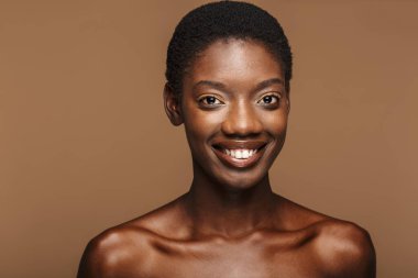 Çekici, yarı çıplak, kısa siyah saçlı, bej arka planda yaşayan Afrikalı bir kadının güzel portresi.