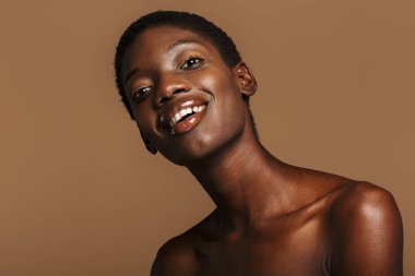 Çekici, yarı çıplak, kısa siyah saçlı, bej arka planda yaşayan Afrikalı bir kadının güzel portresi.