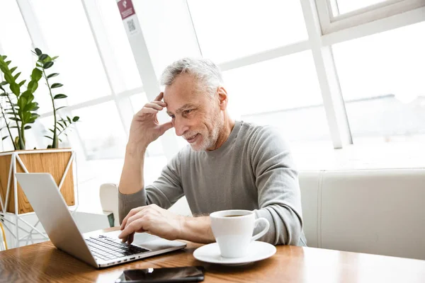 Memnun Bir Yetişkin Adamının Fotoğrafı Kafede Dizüstü Bilgisayarla Oturuyor — Stok fotoğraf