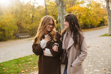 Yeşil doğa parkında gezen, gülümseyen, iyimser genç bayan arkadaşları..