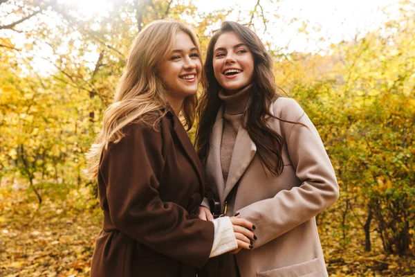 Dos Jóvenes Alegres Chicas Guapas Con Abrigos Caminando Juntas Parque —  Fotos de Stock