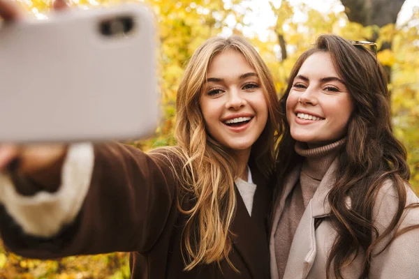 Dos Jóvenes Alegres Chicas Guapas Usando Abrigos Caminando Juntas Bosque —  Fotos de Stock