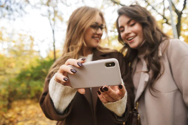 Dos Jóvenes Alegres Chicas Guapas Usando Abrigos Caminando Juntas Bosque —  Fotos de Stock