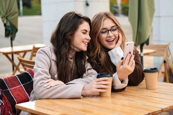 Due Amiche Attraenti Allegre Sedute Caffè All Aperto Guardando Telefono — Foto Stock