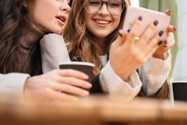 Két Vidám Vonzó Barátok Kávézóban Szabadban Nézi Mobiltelefon Miközben Iszik — Stock Fotó