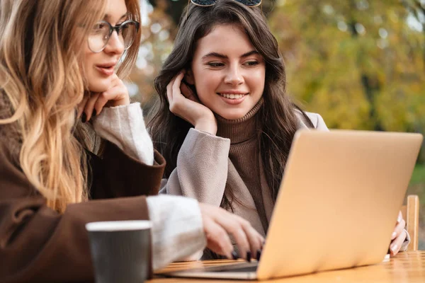 Dvě Veselé Atraktivní Ženy Přátelé Sedí Kavárně Venku Pracuje Notebooku — Stock fotografie