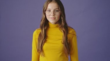 Güzel, neşeli, genç bir kız gülümsüyor. Mor arka planda, stüdyoda.