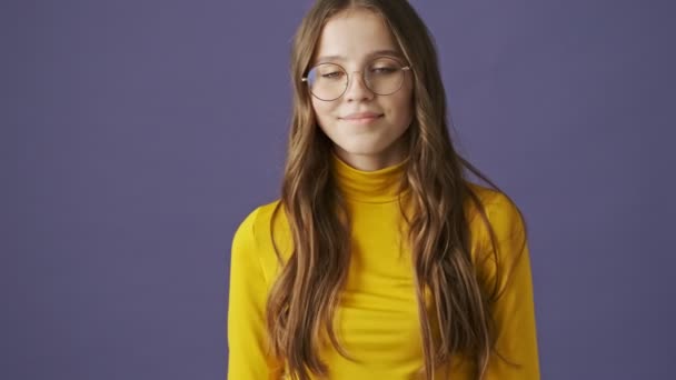 一个快乐微笑的少女站在工作室的紫色背景上做着一个竖起大拇指的手势 — 图库视频影像