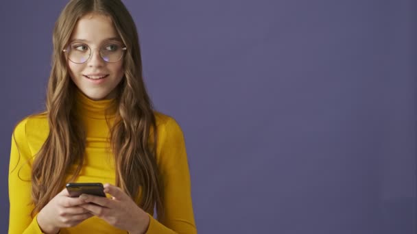 Uma Encantadora Adolescente Satisfeita Está Usando Seu Smartphone Isolado Sobre — Vídeo de Stock