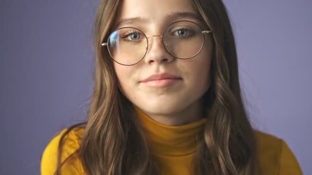 美しい十代の女の子のクローズアップビューは スタジオで紫色の背景の上に隔離されたカメラを探しています — ストック動画