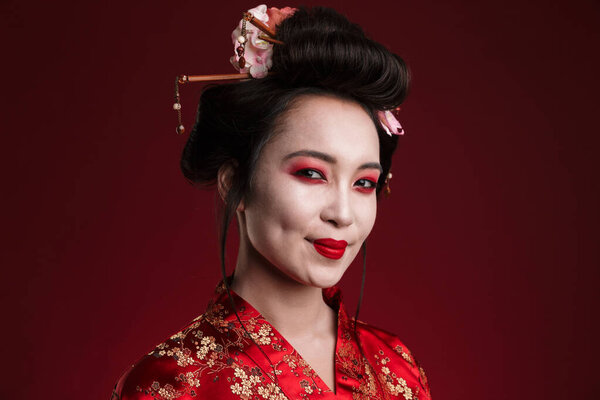 Image of attractive asian geisha woman in traditional japanese kimono isolated over red background