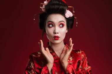 Kırmızı arka planda izole edilmiş geleneksel Japon kimonolu genç bir geyşa resmi.
