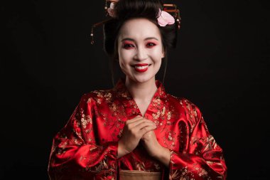 Geleneksel Japon kimonosu giymiş mutlu bir geyşa kadın resmi. Siyah arka planda izole bir şekilde gülümsüyor.