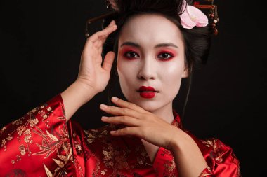 Siyah arka planda geleneksel Japon kimonosuyla dans eden çekici bir geyşa kadın resmi.